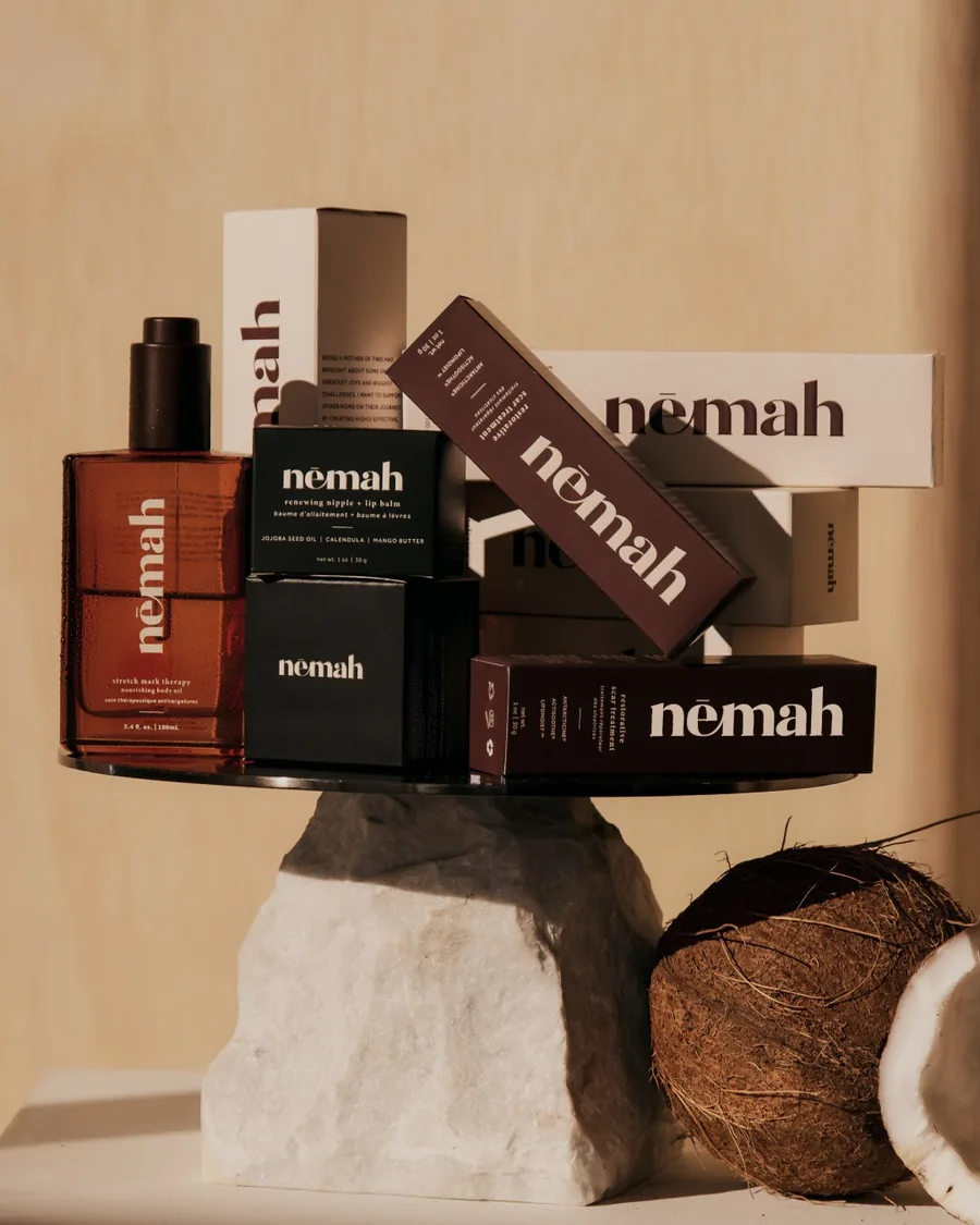 Nemah skincare products arranged on a stone pedestal with coconuts